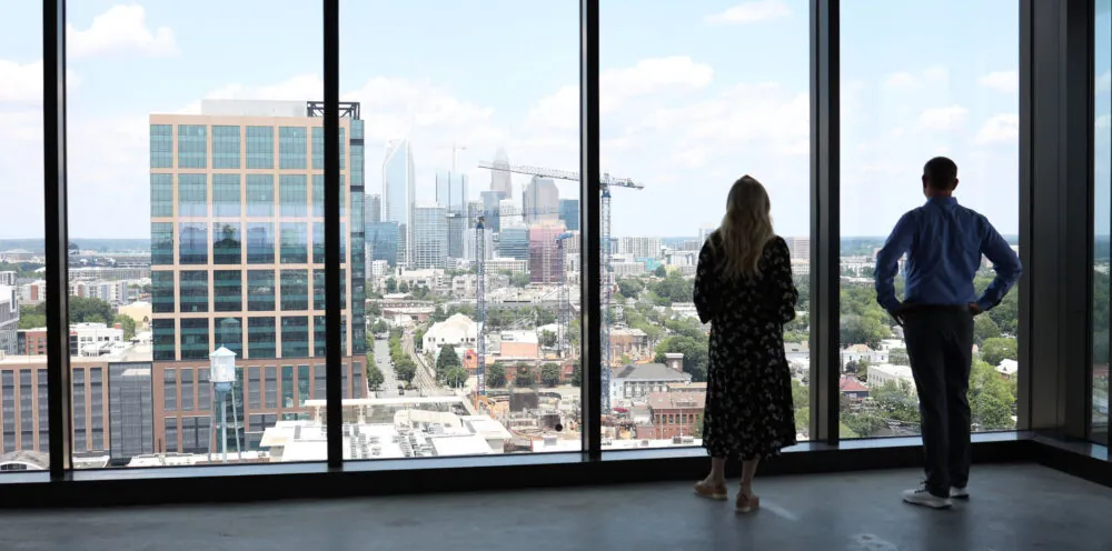 Two colleagues looking out of an office building toward the horizon