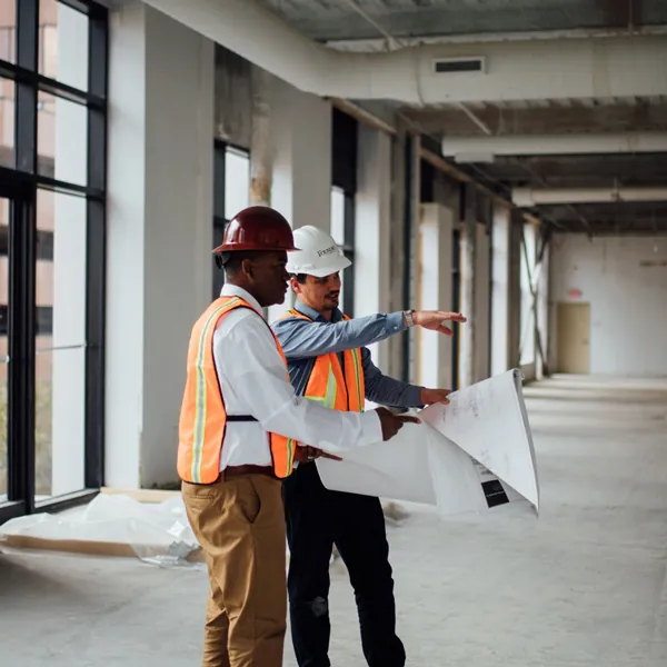 Two men walking through a space under construction